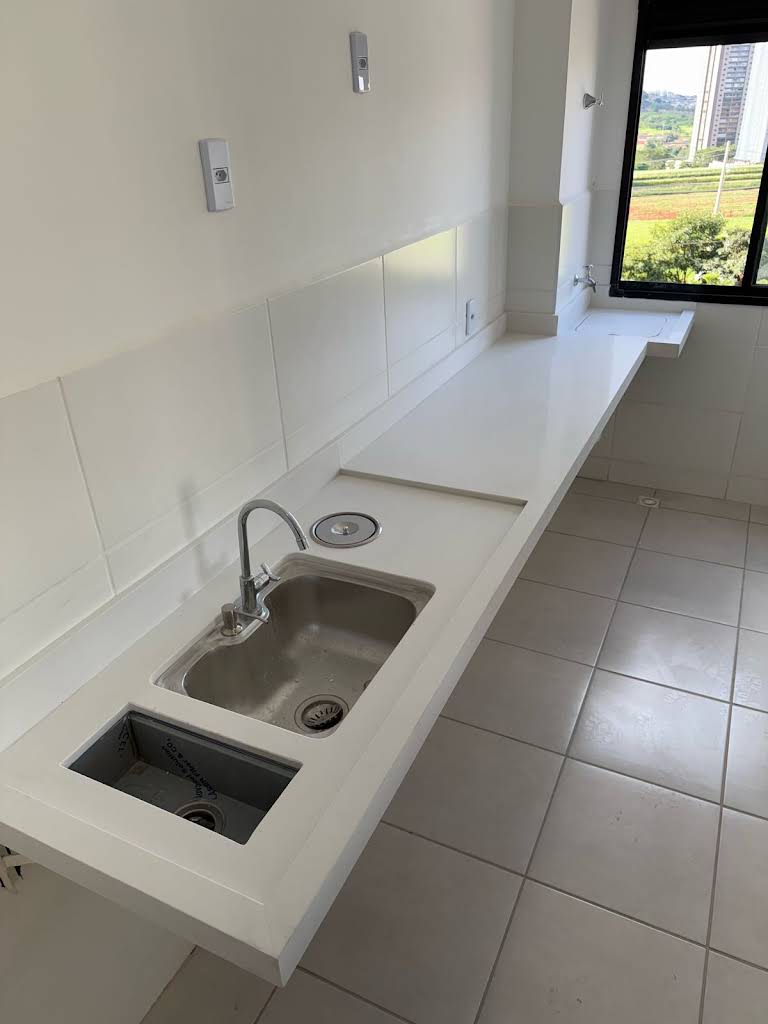Bancada branca comprida instalada em lavanderia com duas cubas