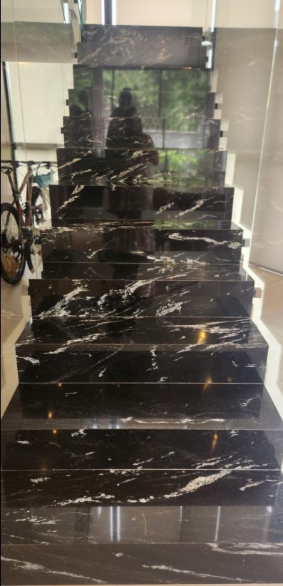 Escada revestida em granito preto com veios brancos marcantes